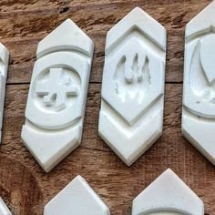 This may contain: six white wax stamps with the letters and symbols carved into them on a wooden surface